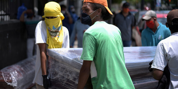 Zwei Männer tragen in Ecuador einen Sarg weg