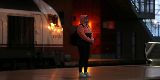 Eine Frau mit Schutzmaske vor einem Zug in Madrid