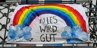 Ein Plakat mit einem Regenbogen und der Aufschrift "alles wird gut" an einem Balkon