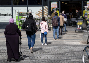 Menschen stehen vor einem Supermarkt an Menschen stehen vor einem Supermarkt an