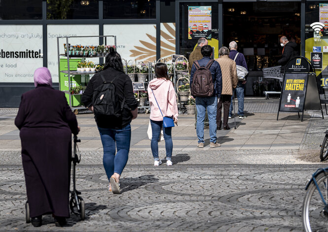 Menschen stehen vor einem Supermarkt an