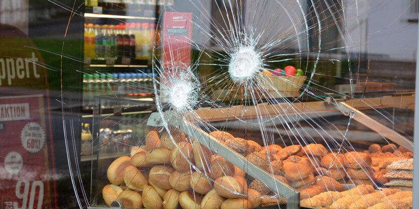 Einschlagstellen von Steinwürfen sind in der Fensterscheibe einer Bäckereifiliale zu sehen.