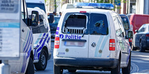Ein belgisches Polizeiauto mit zertrümmerten Heckscheiben steht auf der Straße