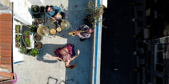 Eine Frau tanzt und zwei Personen musizieren auf einem Balkon in der Türkei