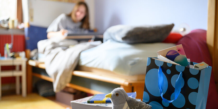 Ein Mädchen sitzt mit Computer in ihrem Bett