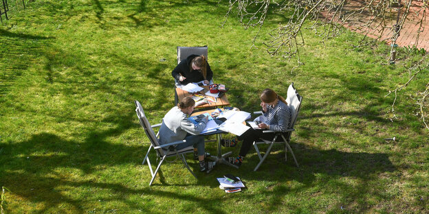 Drei Scülerinnen sitzen im Garten und lernen.