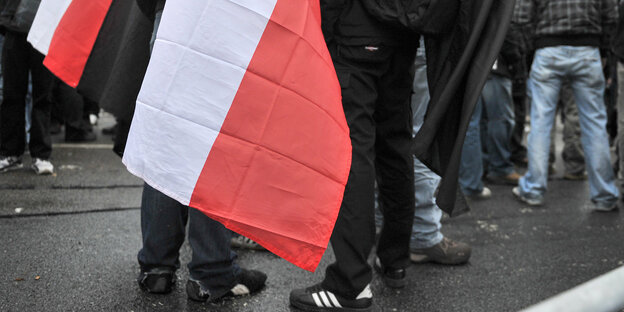 Menschen stehen auf der Straße, im Vordergrund eine Reichskriegsflagge