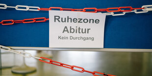 Ein schild hängt vor einer Tafel mit der Aufschrift Abitur bitte ruhe