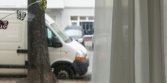 Blick aus dem Fenster einer Erdgeschosswohnung. Vor dem Fenster steht ein weißer Lieferwagen