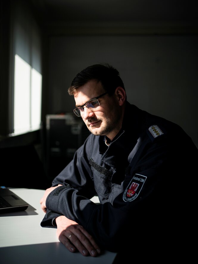 Ein Mann in Feuerwehruniform sitzt an einem Schreibtisch