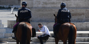 2 Polizisten stören einen Mann, der auf sein Handy schaut