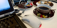 Süßigkeiten, Kaffee und Kekse stehen neben einem Laptop auf einem Tisch - so könnte es im Homeoffice aussehe