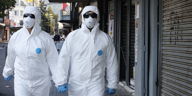 ein Paar in weisser Schutzkleidung geht auf der Straße spazieren