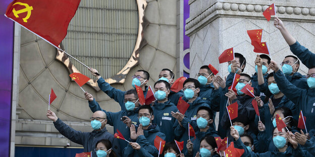 Männer in Uniform und Masken winken mit kleinen Fähnchen der Volksrepublik China
