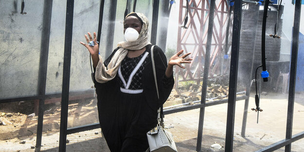 Kenia, Mombasa: Eine Frau geht auf ihrem Weg zu einer Fähre durch eine automatische Desinfektions-Installation. Alle Passagiere die am Hafen von Mombasa ankommen oder abfahren wollen, sollen desinfiziert werden, um die Ausbreitung des Coronavirus einzudäm