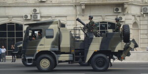 LKW mit Camouflage-Markierung und Mörser vor Hauswand