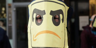 Ein Mann trägt eine Maske mit einem Amazonlogo das weint