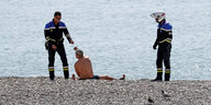 Polizisten kontrollieren einen Mann am Strand in Nizza