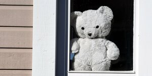 Grosser weisser Teddybär schaut aus dem Fenster