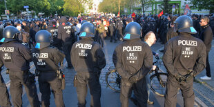 Polizisten in voller montur stehen vor einer Gruppe von Demonstranten