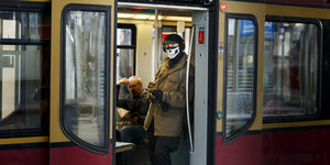 Ein Mann trägt in der S-Bahn im Bahnhof Alexanderplatz einen Munschutz auf dem Teile eine Totenkopfs abgebildet sind.
