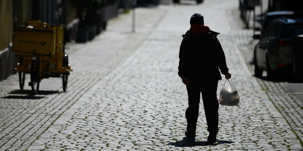 Ein Mann geht allein mit sienen Einkkäufen die Straße entlang
