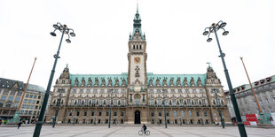 Auf dem menschenleeren Rathausmarkt fährt vor der Kulissse des Rathauses jemand Rad