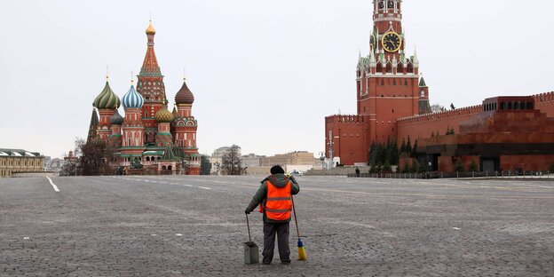 Der Rote Platz in Moskau, fast menschenleer. In der Mitte nur eine Person mit roter Jacke und Kehreimer.