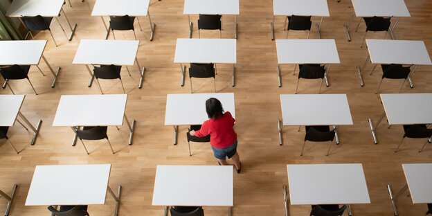 viele Tische stehen voneinander getrennt in einem Klassenzimmer
