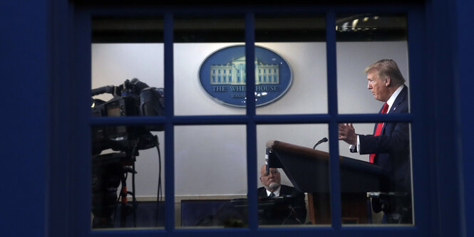 US-Präsident Donald Trump bei einer Pressekonferenz im Weißen Haus, fotografiert durch ein Fenster.