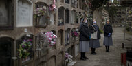 Drei Frauen in Nonnentracht mit Atmenschutzmaske auf einem Friedhof in Spanien