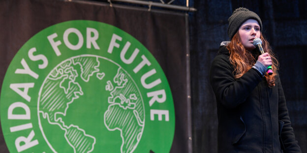 Neubauer mit Mikro auf einer Bühne vor großem grünem "Fridays for Future"-Logo