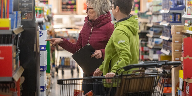 Frauen mit Einkaufswagen vor Supermarktregal