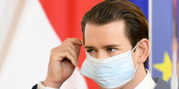 Österreichs Kanzler Sebastian Kurz zieht sich eine Atemschutzmaske an.