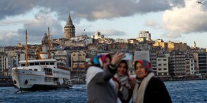 Vor der Skyline Istanbuls machen drei ältere Frauen ein Selfie.