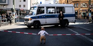Ein kleines Kind vor einer Polizeiabsperrung.