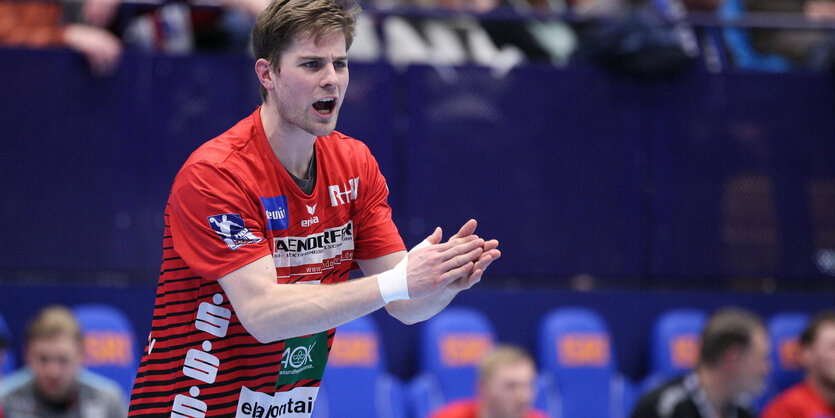 Ein Handballer auf dem Spielfeld klatscht in die Hände