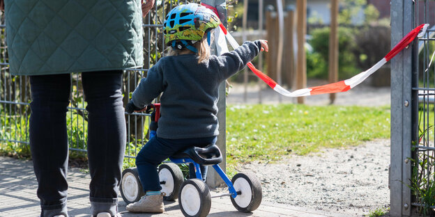 Ein Kind sitzt auf einem Dreirad und zeigt mit einer Hand aus dem foto heraus