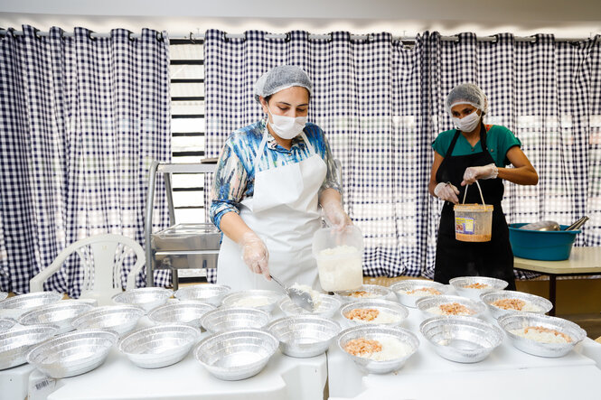 Juliana da Costa Gomes füllt Essen in Alubehälter.