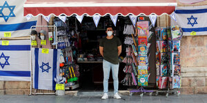 Ein Mann mit Mundschutz steht vor einem Kiosk