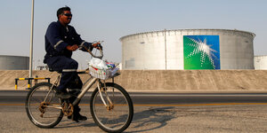 Ein Arbeiter auf einem Rad vor einem Öltank.