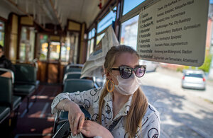 eine Frau in einer Straßenbahn trägt eine Schutzmaske