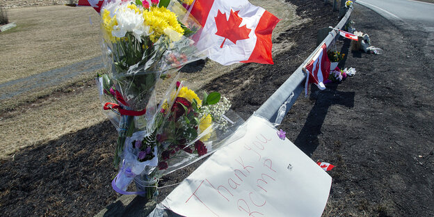 An einer Leitplanke sind Blumen und die kanadische Flagge befestigt.