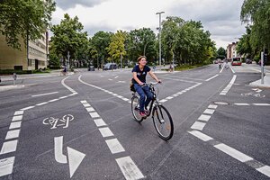 Fahrradfahrerin an der Zusammenführung zweier abmarkierter Radwege mitten auf einer Kreuzung