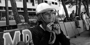 Rennfahrerin mit Helm auf einem historischen Foto.