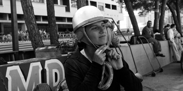 Rennfahrerin mit Helm auf einem historischen Foto.