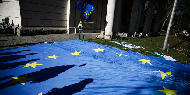 Europäische Fahne auf einer Wiese, ein Kind schwingt eine kleine Europaflagge