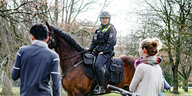 Eine Polizistin auf Pferd spricht mit Passanten