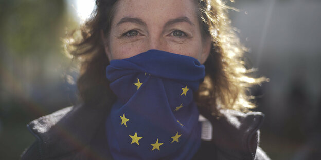 Frau mit einem blauen Tuch vor dem Mund und Europasternen