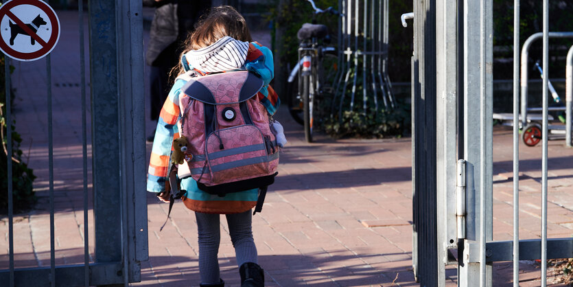 Kind mit Schulranzen im Schultor